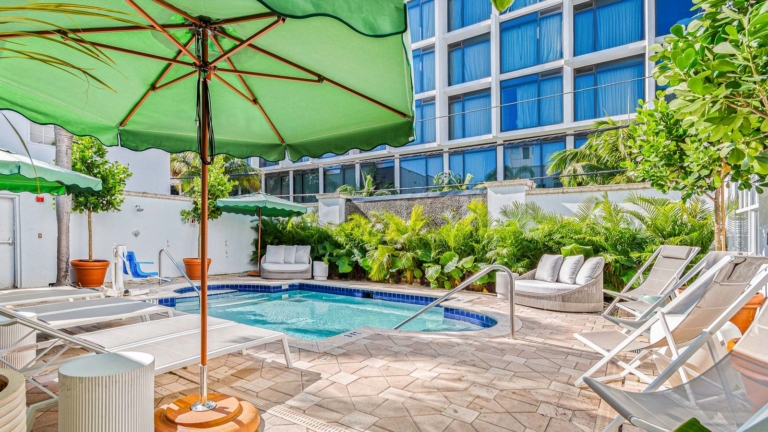 Outdoor swimming pool and pool deck with green parasols at Corendon South Beach Miami